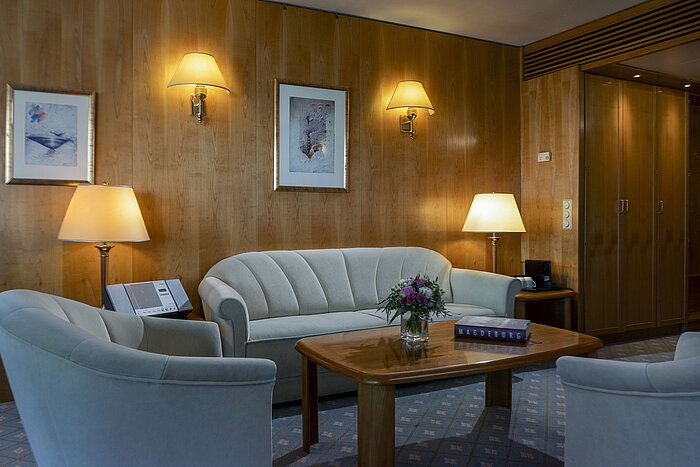 Gemütliche Sitzecke in einer Suite des Maritim Hotel Magdeburg mit eleganter Einrichtung und warmem Ambiente.