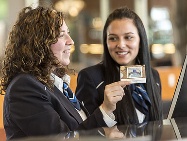 Rezeptionsmitarbeiterinnen des Maritim Hotel Frankfurt lächelnd, während sie eine Zimmerkarte präsentieren.