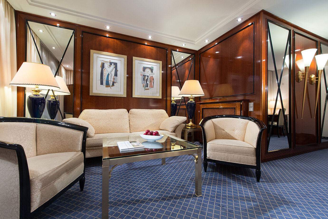 Eleganter Wohnbereich einer Suite im Maritim Hotel Fulda mit stilvollen Möbeln, Glas-Couchtisch und gemütlicher Beleuchtung.