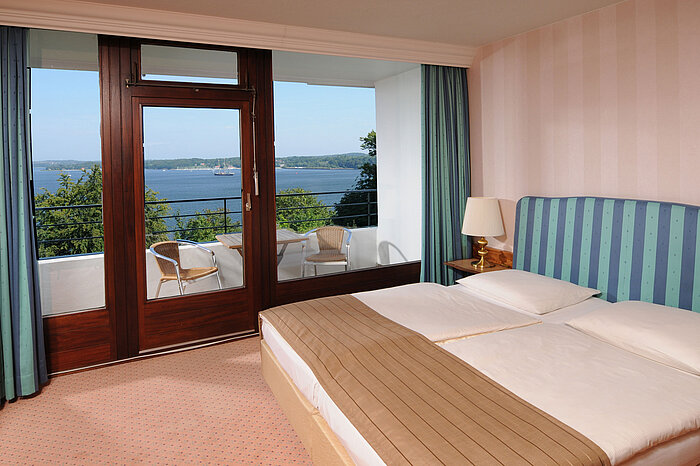 Junior Suite Junior Suite im Maritim Hotel Kiel, Doppelbett, Balkon mit Sitzgelegenheiten und Blick auf die Kieler Förde.