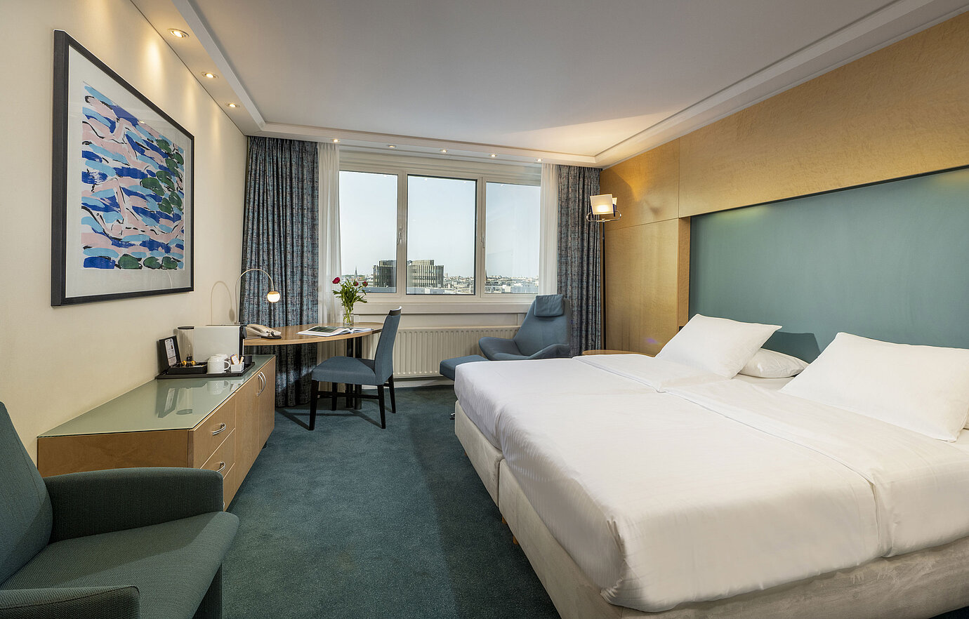 Modern eingerichtetes Superior-Zimmer im Maritim proArte mit großem Bett, Schreibtisch, Kunstwerk und Blick auf die Stadt.