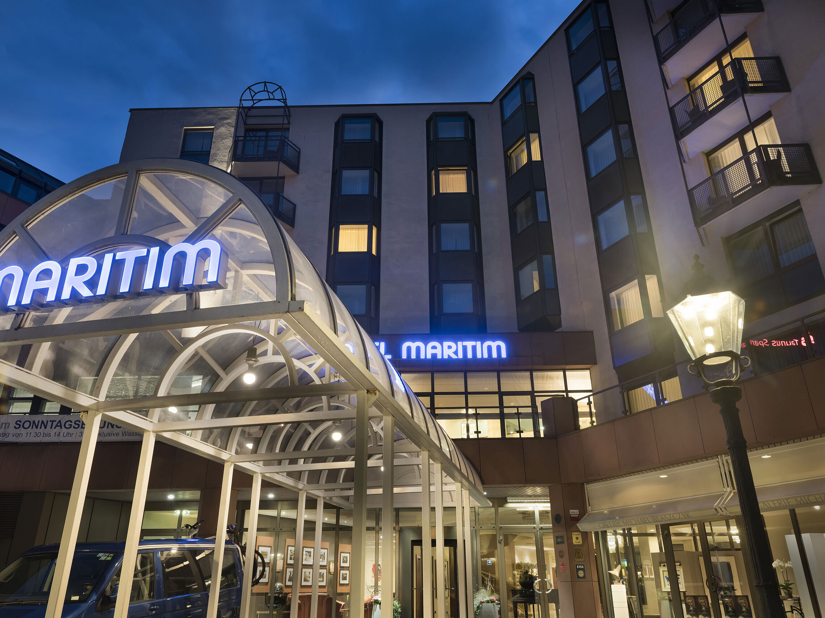 Detailansicht des beleuchteten Eingangsbereichs im Maritim Hotel Bad Homburg bei Nacht.