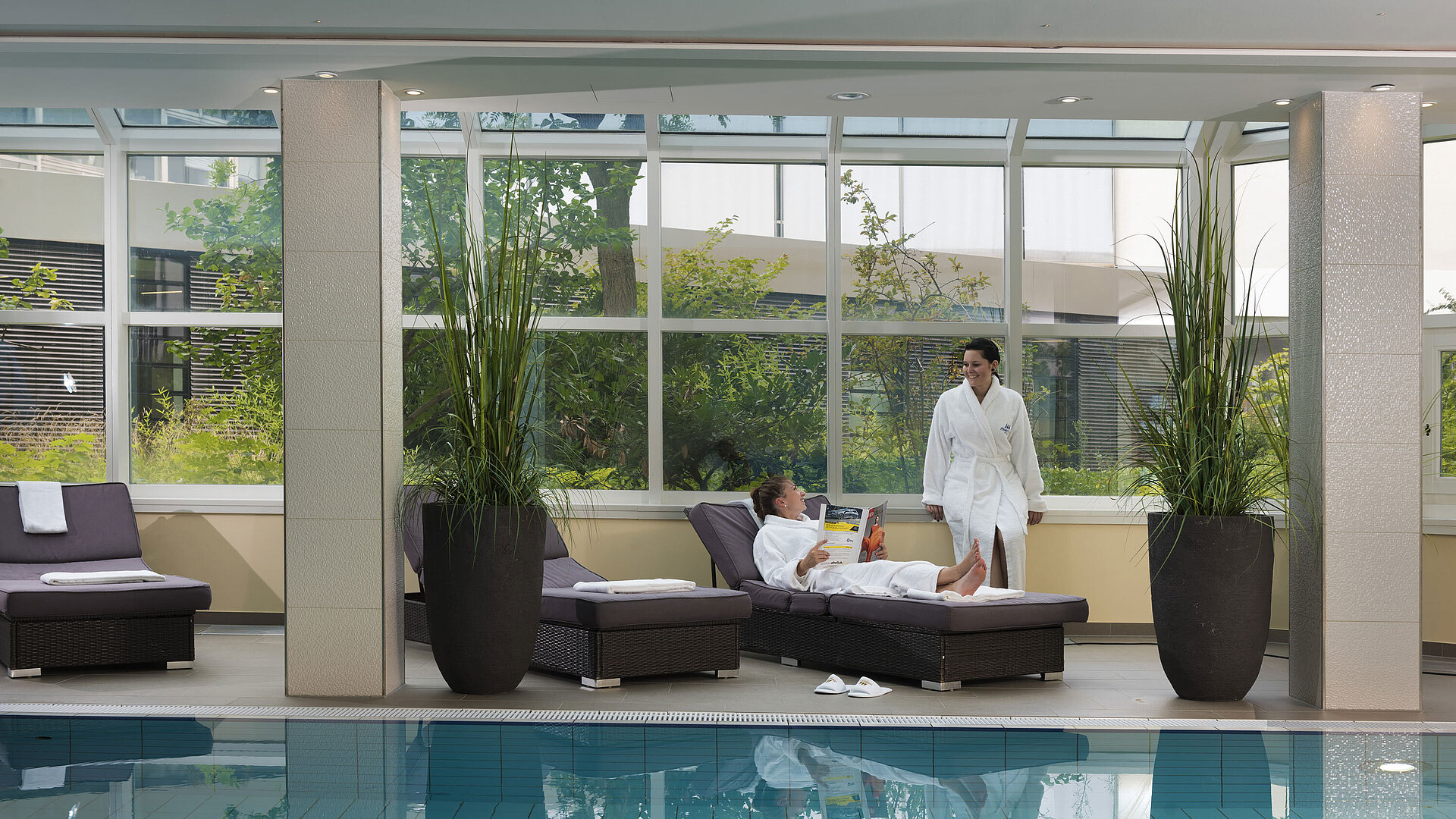 Ruhebereich mit Pool und Liegen im Maritim Hotel Würzburg – zwei Gäste entspannen in Bademänteln.