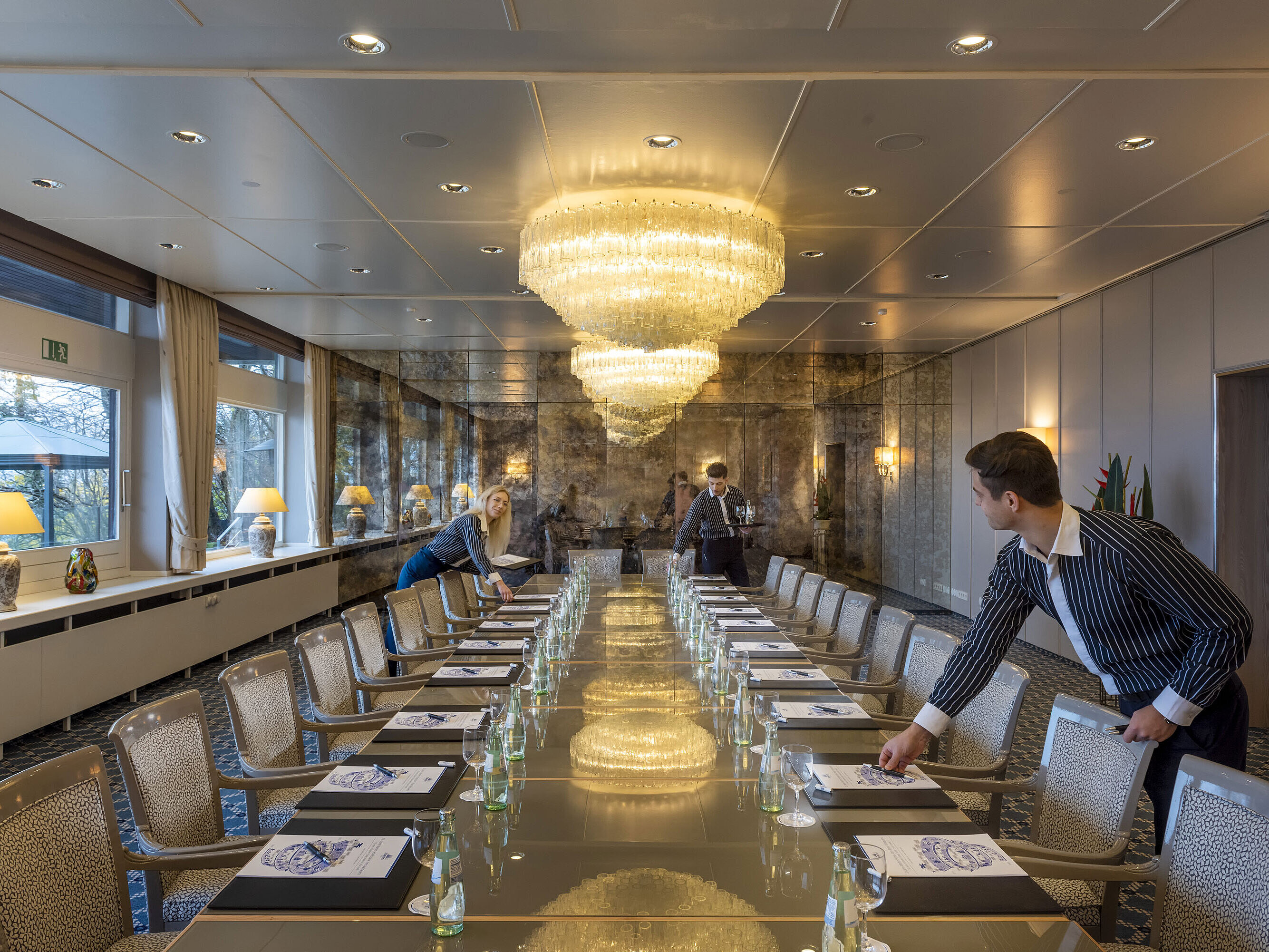 Salon Oslo im Maritim Hotel Kiel, eleganter Konferenzraum mit Kronleuchtern und langer Tischreihe, Personal richtet den Raum ein.