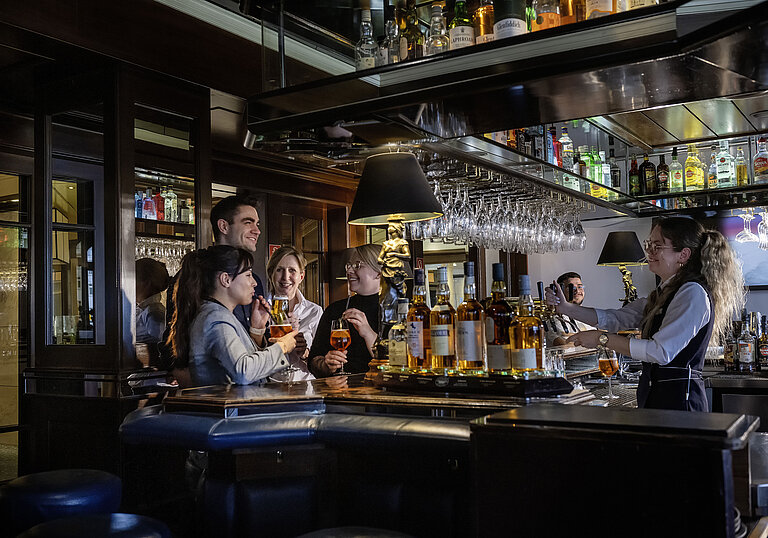 Gäste genießen Cocktails und gute Stimmung in der Bar des Maritim Hotels Darmstadt. Freundliches Barpersonal serviert Drinks.