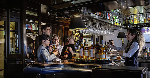 Gäste genießen Cocktails und gute Stimmung in der Bar des Maritim Hotels Darmstadt. Freundliches Barpersonal serviert Drinks.