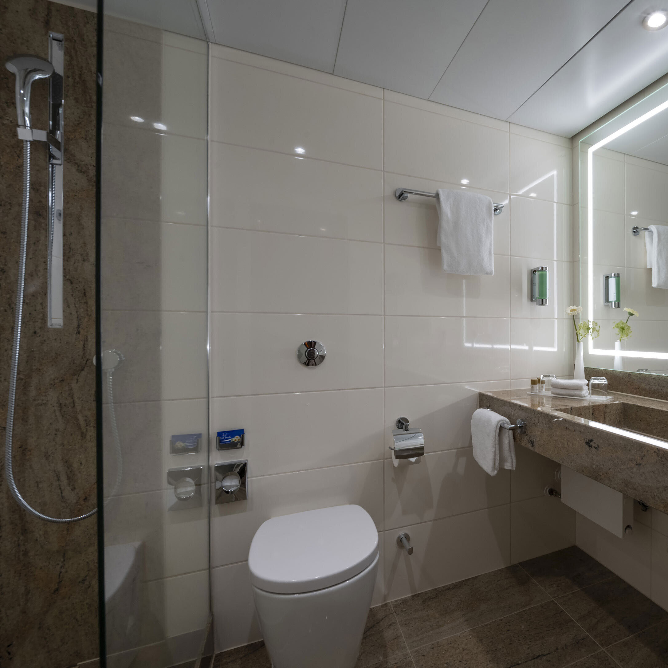 Comfort Bad Modernes Badezimmer im Maritim Hotel Bremen mit luxuriösen Armaturen, großem Spiegel mit Beleuchtung und ebenerdiger Dusche.