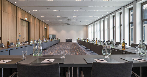 Moderner Tagungsraum im Maritim Hotel Ingolstadt mit großen Fenstern, U-förmiger Bestuhlung und Tagungsmaterialien.