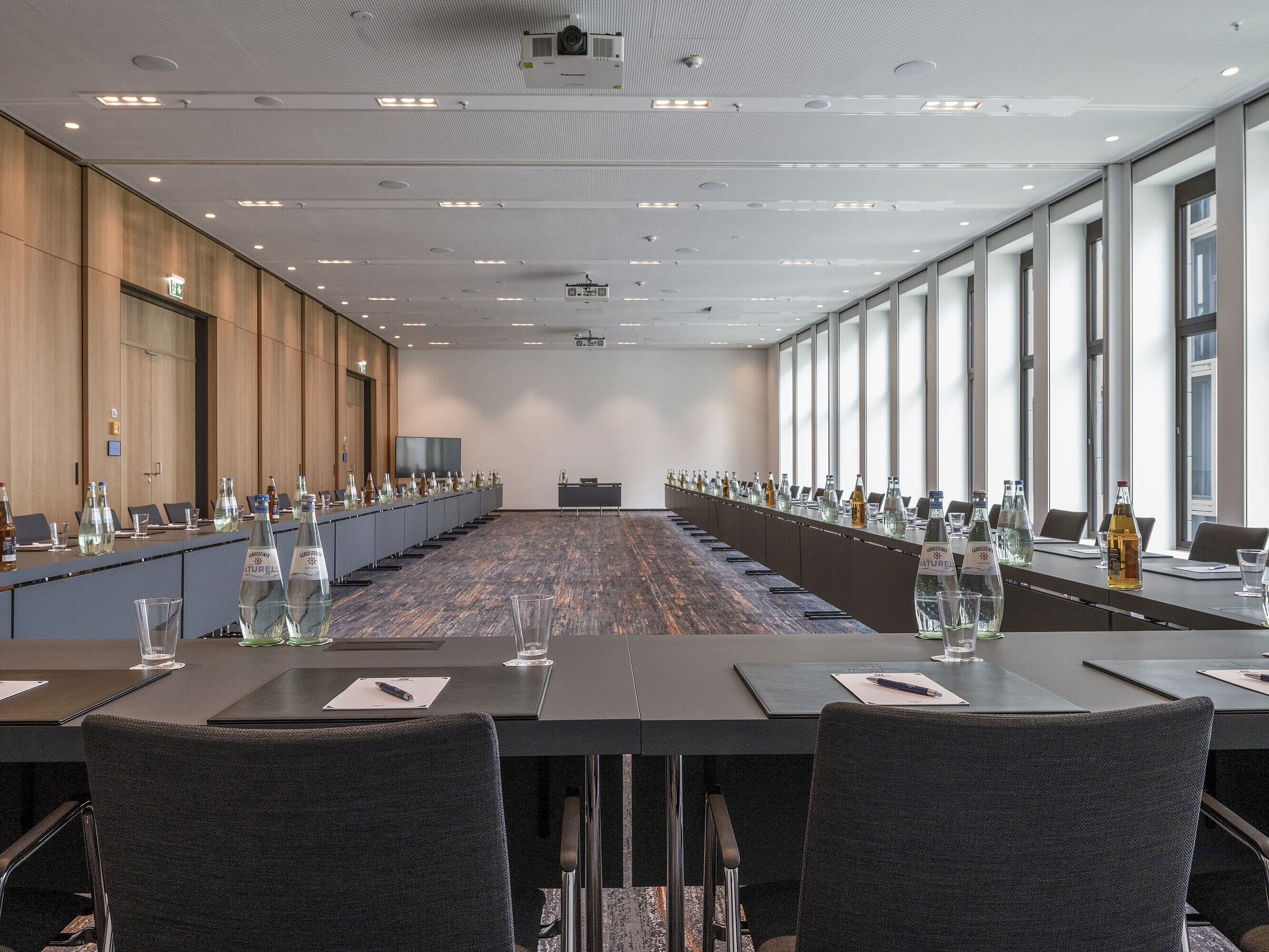 Moderner Tagungsraum im Maritim Hotel Ingolstadt mit großen Fenstern, U-förmiger Bestuhlung und Tagungsmaterialien.