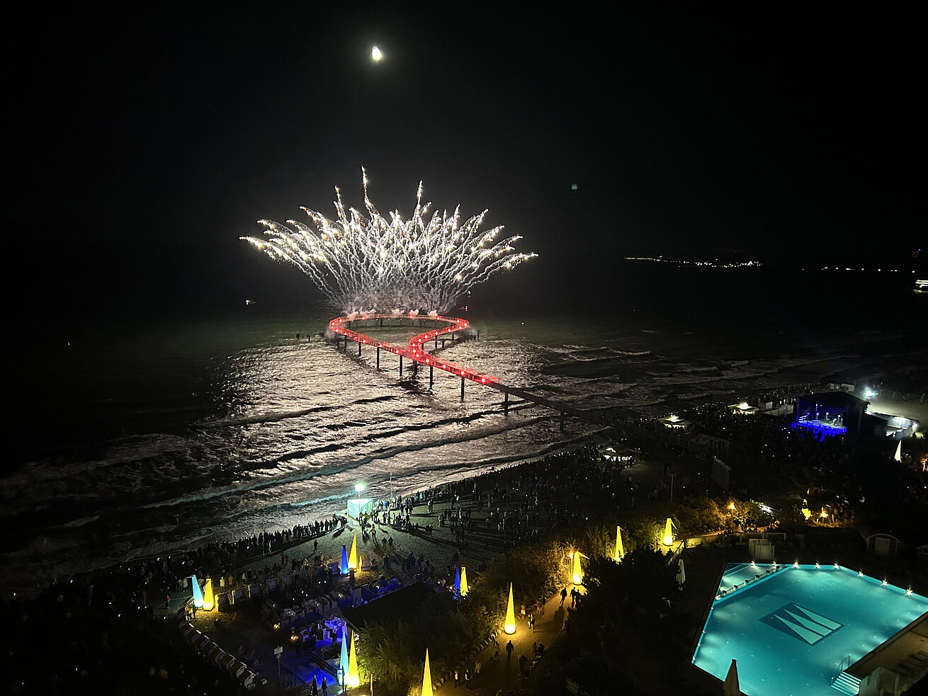 Spektakuläres Feuerwerk über der Seebrücke am Maritim Seehotel Timmendorfer Strand bei Nacht mit Pool und feiernden Gästen.