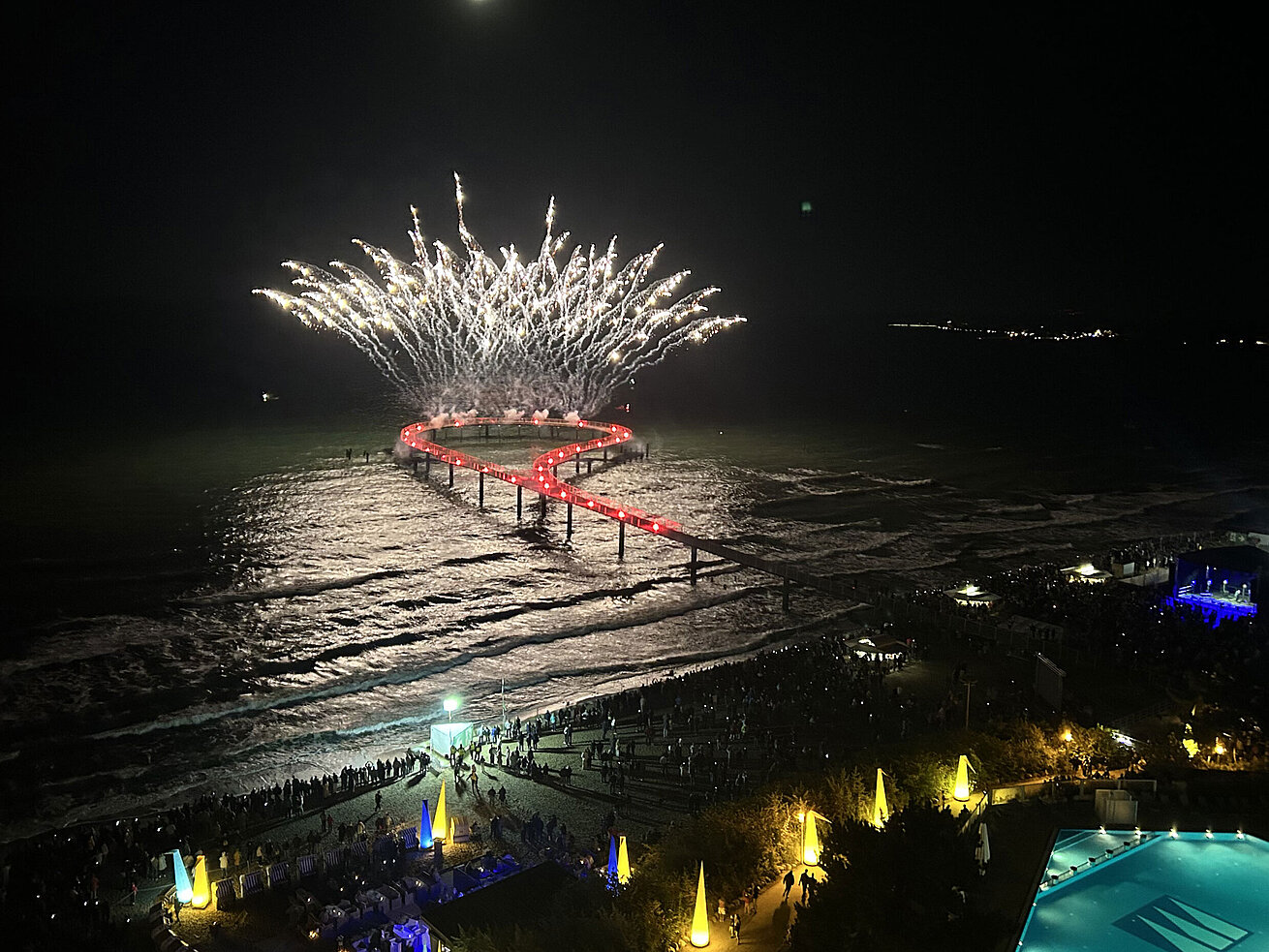 Spektakuläres Feuerwerk über der Seebrücke am Maritim Seehotel Timmendorfer Strand bei Nacht mit Pool und feiernden Gästen.