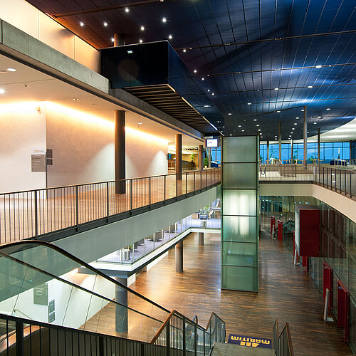 Modernes, beleuchtetes Atrium im Maritim Hotel Dresden mit Rolltreppen und Glasarchitektur.