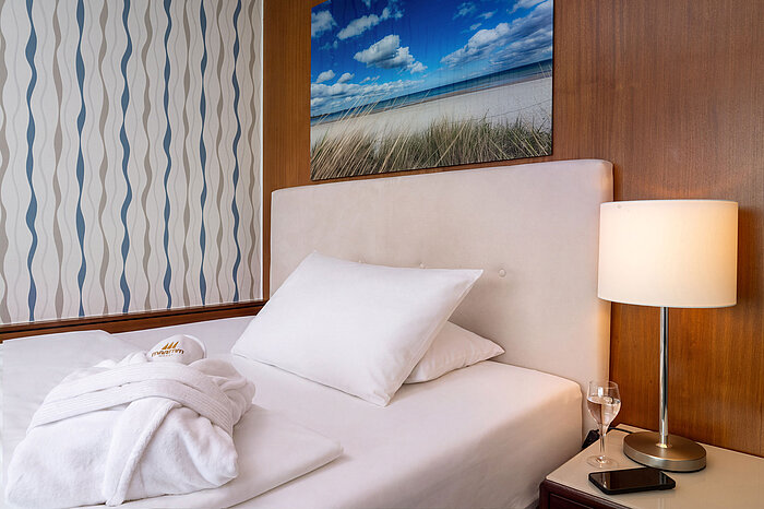 Queensize-Bett im Superior Queen Zimmer mit Nachttischlampe und Bademantel
