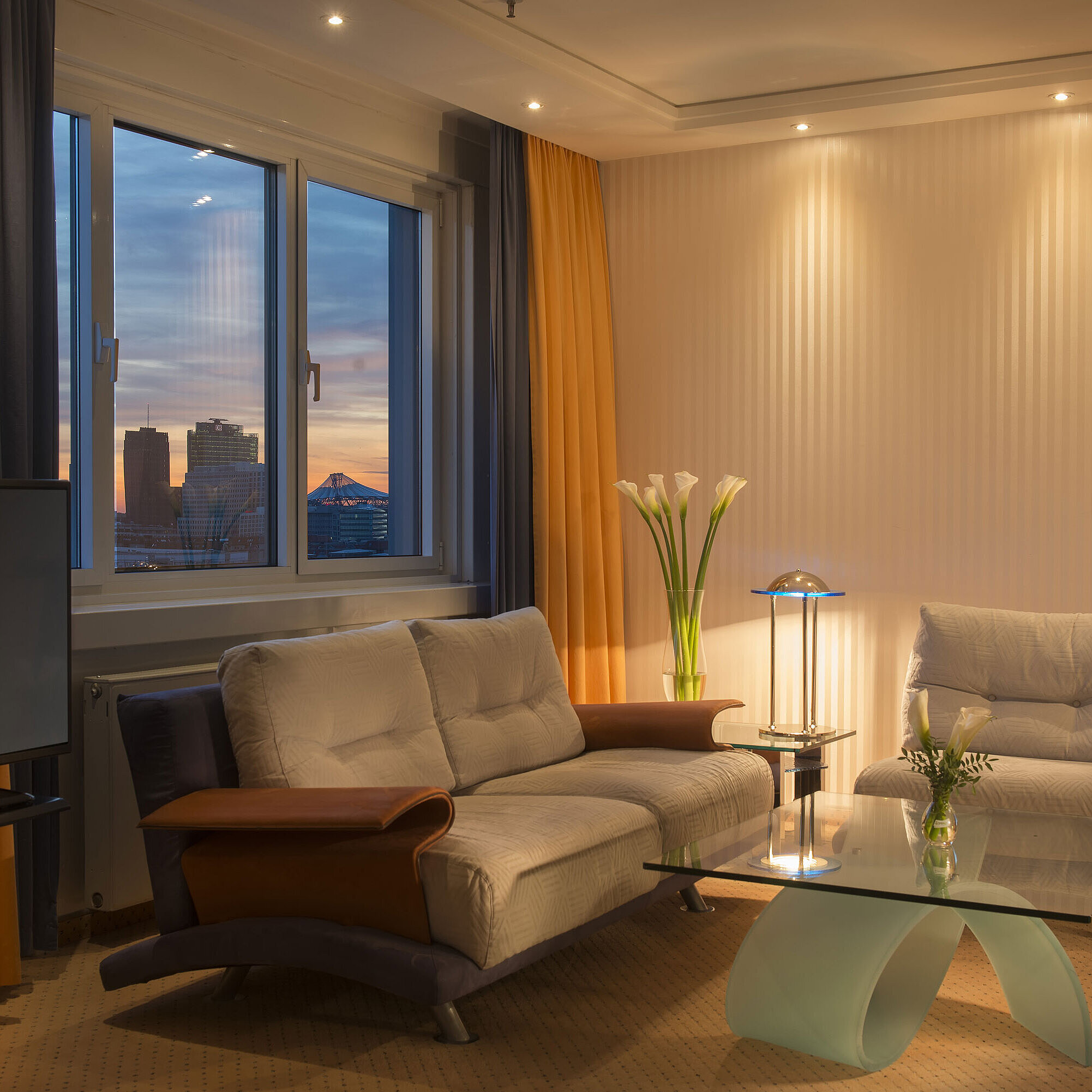 Peter-Kuckei-Suite Sitzecke mit Ausblick in der Kuckei-Suite im Maritim proArte Hotel Berlin bei Sonnenuntergang.