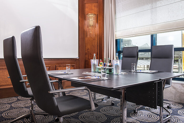 Moderner Meetingraum mit großem Tisch, Ledersesseln und Tageslicht im Maritim Hotel Hannover.