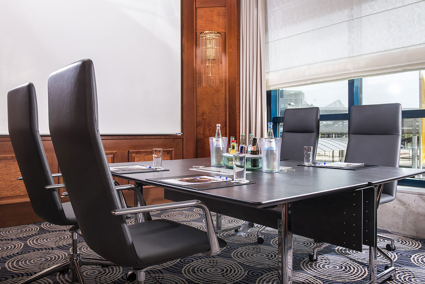 Moderner Meetingraum mit großem Tisch, Ledersesseln und Tageslicht im Maritim Hotel Hannover.