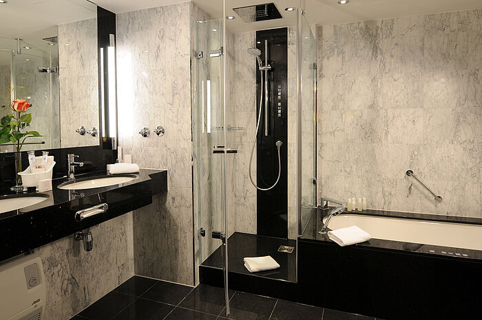 Modernes Bad mit Marmorfliesen, Dusche, Badewanne und Doppelwaschbecken im Maritim Hotel München