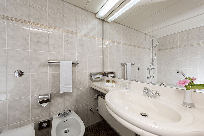 Helles Badezimmer mit Bidet, Waschbecken, Spiegel und frischen Handtüchern im Maritim Hotel Bad Wildungen