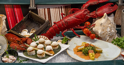 Hummer und Meeresfrüchte-Delikatessen am Buffet des Maritim proArte Hotel Berlin, dekoriert mit Tomaten und Muscheln.