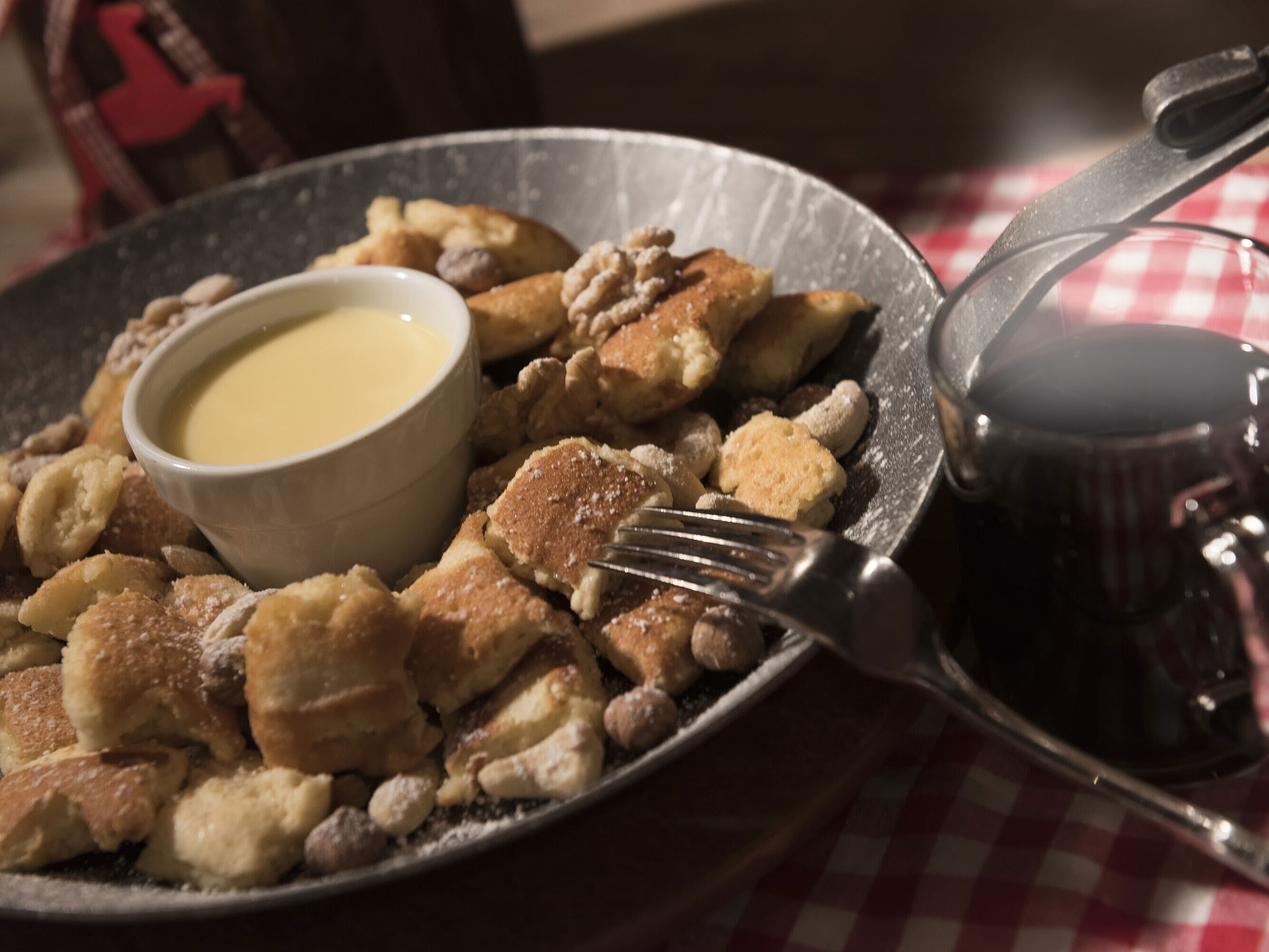 Frischer Kaiserschmarrn mit Nüssen, Puderzucker und Vanillesauce, serviert mit Glühwein in der Maritim Alm