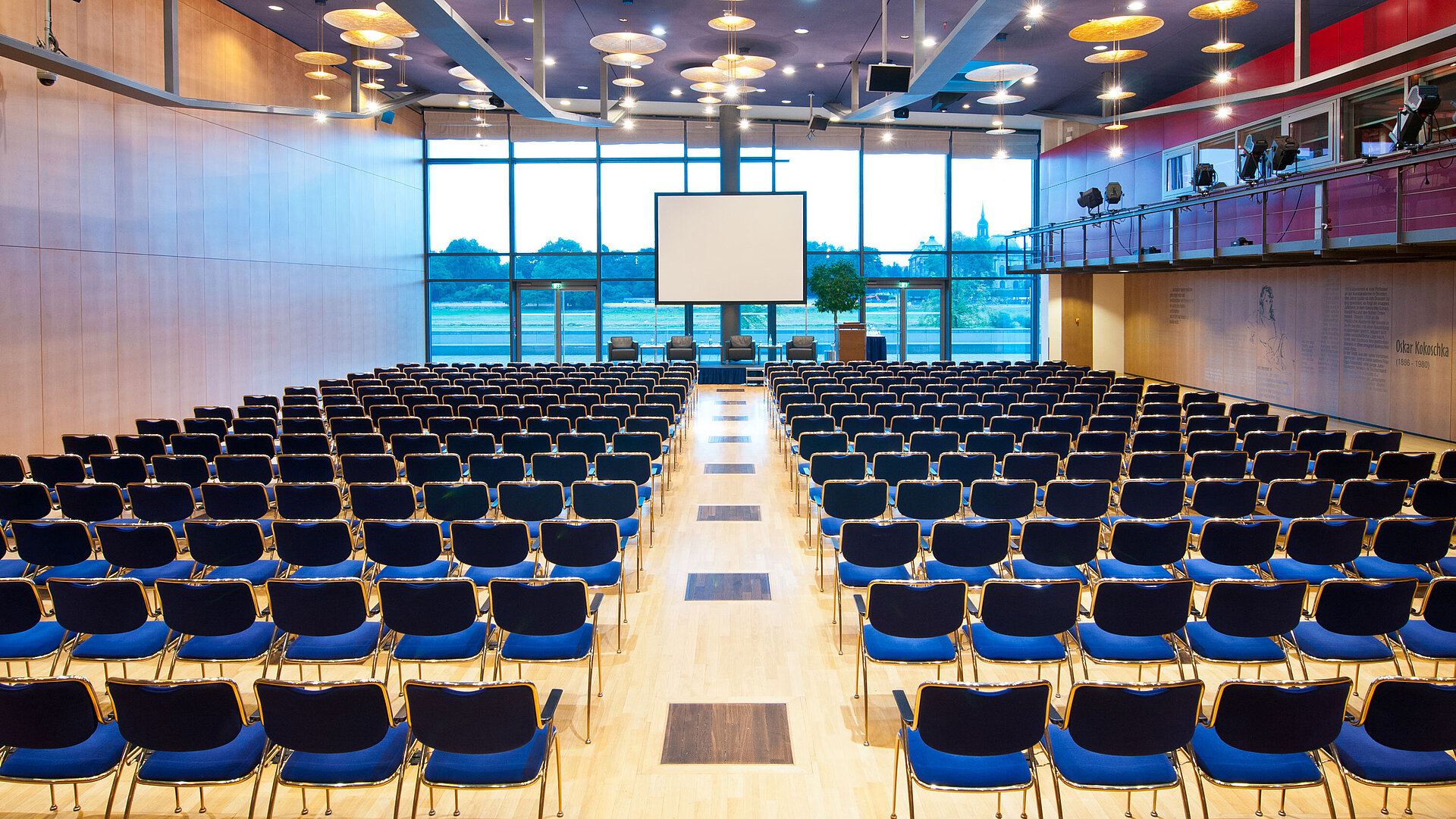 Großer Konferenzsaal im Maritim Hotel Dresden mit Reihen blauer Stühle und Blick auf die Elbe.