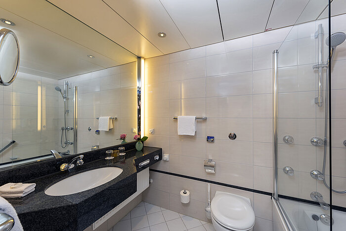 Modernes Badezimmer im Maritim Hotel Frankfurt mit großer Spiegelwand, stilvollem Waschbecken und Dusch-Badewanne.