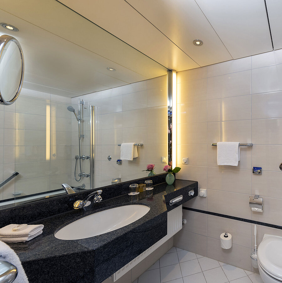 Badezimmer Modernes Badezimmer im Maritim Hotel Frankfurt mit großer Spiegelwand, stilvollem Waschbecken und Dusch-Badewanne.