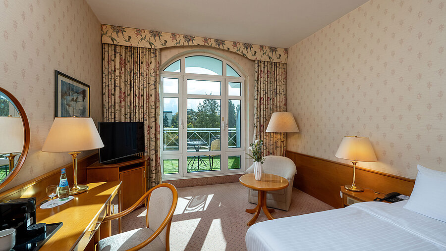 Superior Einzelzimmer mit Bett, Schreibtisch, großem Fenster, Balkonblick und klassischer Einrichtung.