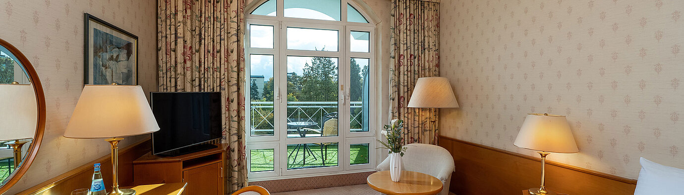 Superior Einzelzimmer Superior Einzelzimmer mit Bett, Schreibtisch, großem Fenster, Balkonblick und klassischer Einrichtung.