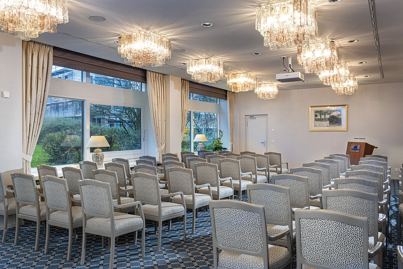 Salon Helsinki im Maritim Hotel Kiel, Konferenzraum mit Stuhlreihen, Kronleuchtern und großen Fenstern mit Blick ins Grüne.