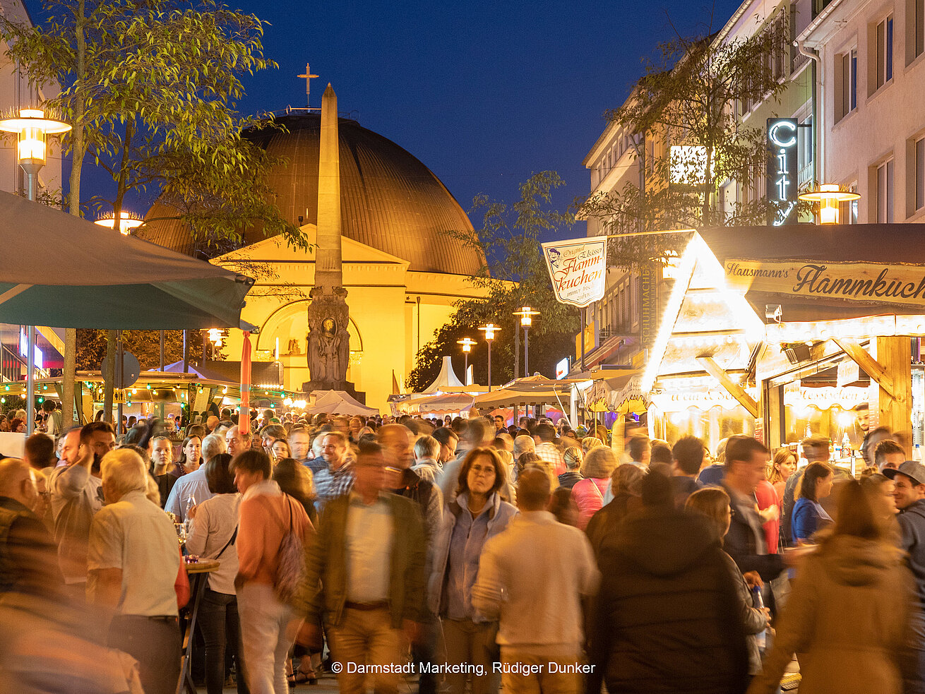 Belebtes Stadtfest mit Marktständen und Kirche bei Nacht