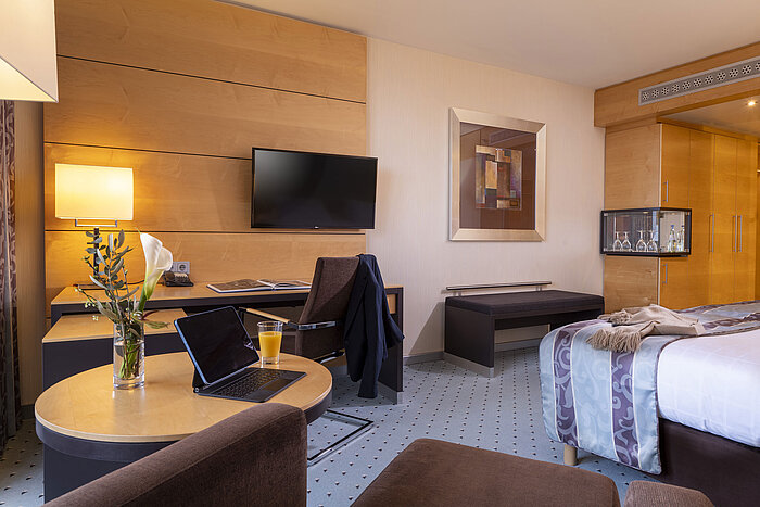 Comfort Zimmer im Maritim Hotel Düsseldorf mit Schreibtisch, Flachbild-TV, gemütlichem Sessel und eleganter Einrichtung.