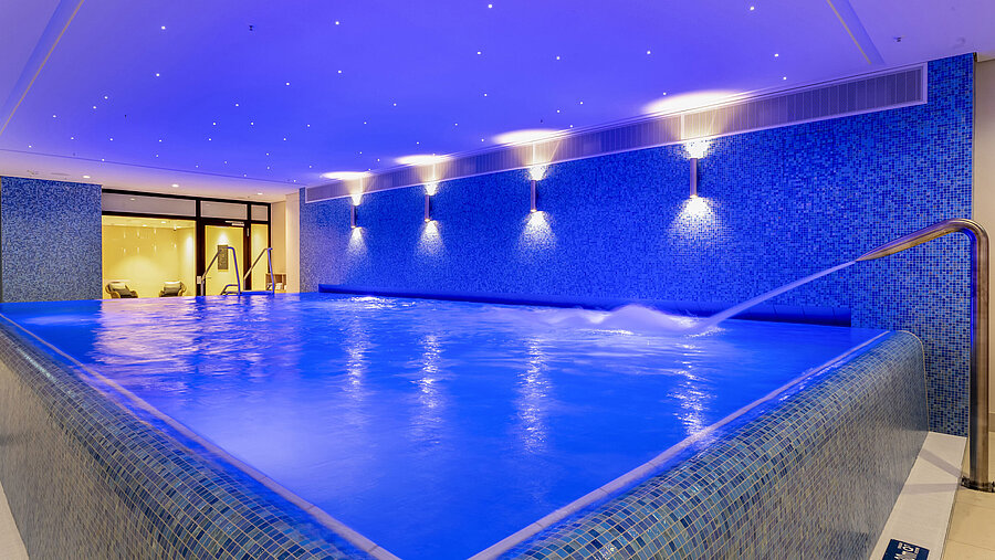 Beleuchteter Infinity-Pool im Maritim Hotel Ingolstadt mit entspannendem Wasserstrahl.