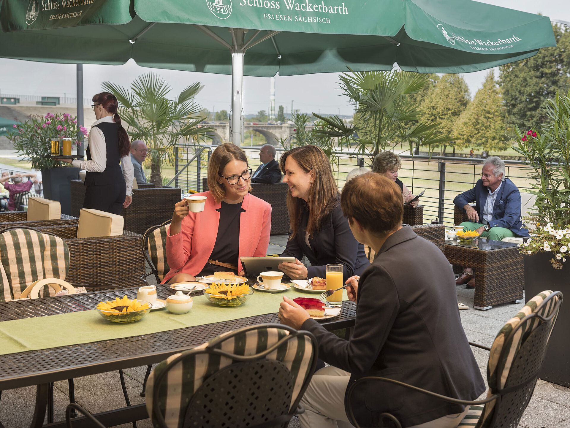 Restaurant "Wintergarten" mit Elbterrasse Gäste entspannen bei Kaffee und Kuchen auf der sonnigen Terrasse des Maritim Hotel Dresden mit Blick ins Grüne.