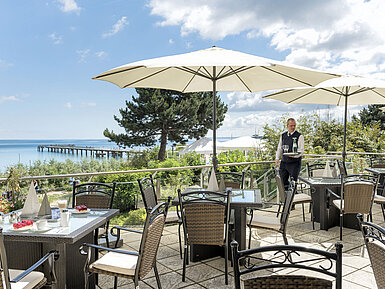 Restaurantterrasse mit Meerblick und Sonnenschirmen im Maritim Seehotel Timmendorfer Strand.