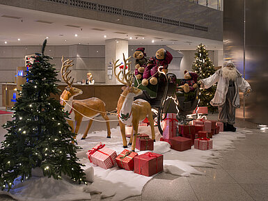 Festliche Dekoration in der Lobby des Maritim proArte Hotel Berlin mit Weihnachtsmann, Rentieren und Geschenken.