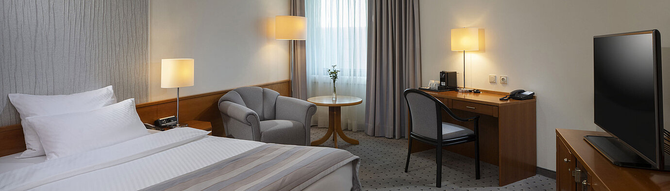 Geräumiges Superior Zimmer mit Bett, Schreibtisch, TV und warmem Lichtdesign im Maritim Hotel Hannover.