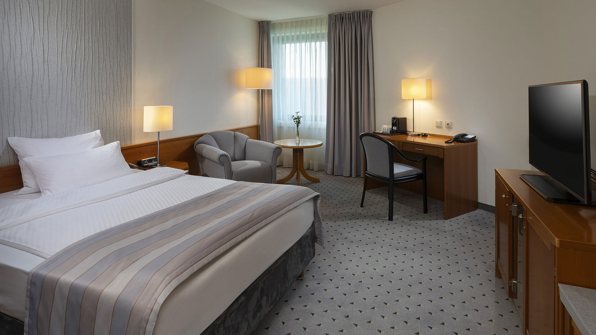 Geräumiges Superior Zimmer mit Bett, Schreibtisch, TV und warmem Lichtdesign im Maritim Hotel Hannover.