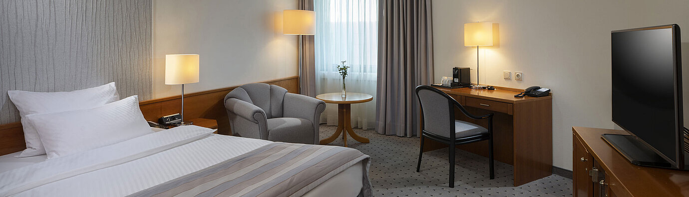 Geräumiges Superior Zimmer mit Bett, Schreibtisch, TV und warmem Lichtdesign im Maritim Hotel Hannover.