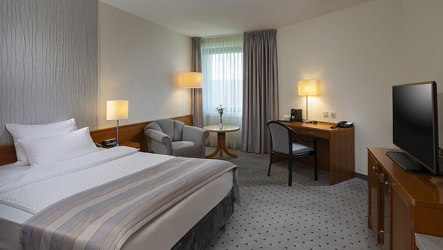 Geräumiges Superior Zimmer mit Bett, Schreibtisch, TV und warmem Lichtdesign im Maritim Hotel Hannover.