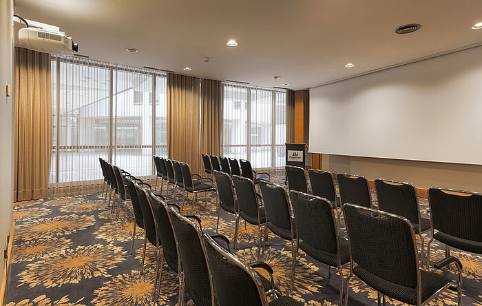 Moderner Seminarraum mit Reihenbestuhlung, Tageslicht und Projektionsfläche im Maritim Hotel Ulm.