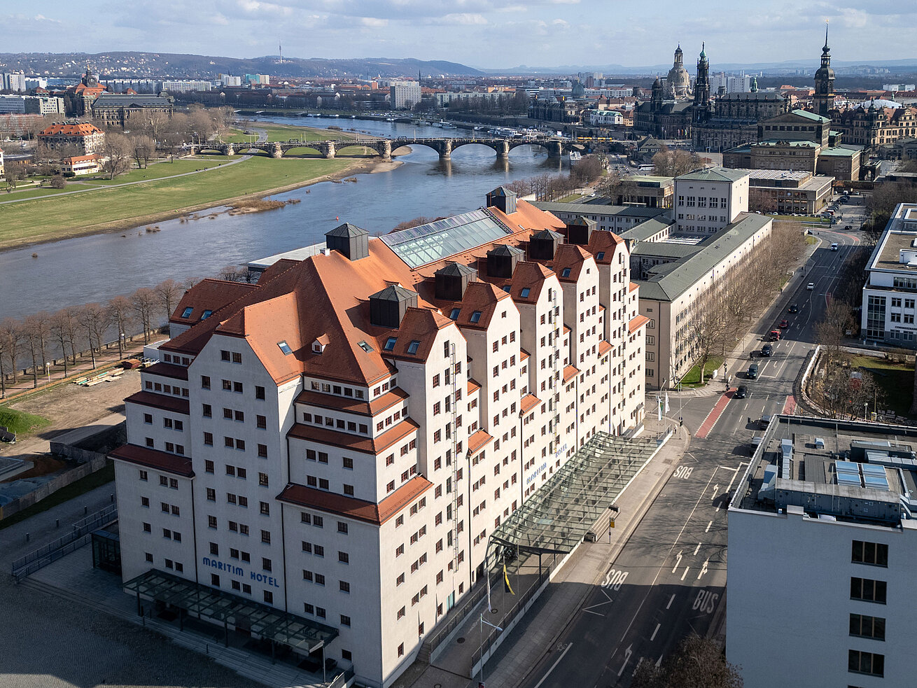 Außenansicht des Maritim Hotel Dresden mit charakteristischer Architektur direkt an der Elbe und Blick auf die Altstadt.