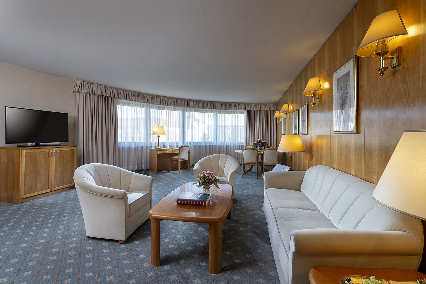 Großzügiges Wohnzimmer einer Suite im Maritim Hotel Magdeburg mit eleganter Einrichtung, Sitzecke und Arbeitsplatz.