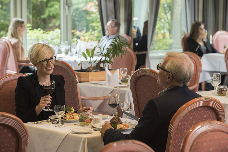 Gäste beim Abendessen im stilvollen Restaurant des Maritim Hotel Bad Salzuflen mit Blick ins Grüne