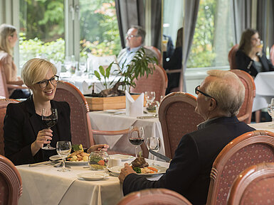 Gäste beim Abendessen im stilvollen Restaurant des Maritim Hotel Bad Salzuflen mit Blick ins Grüne