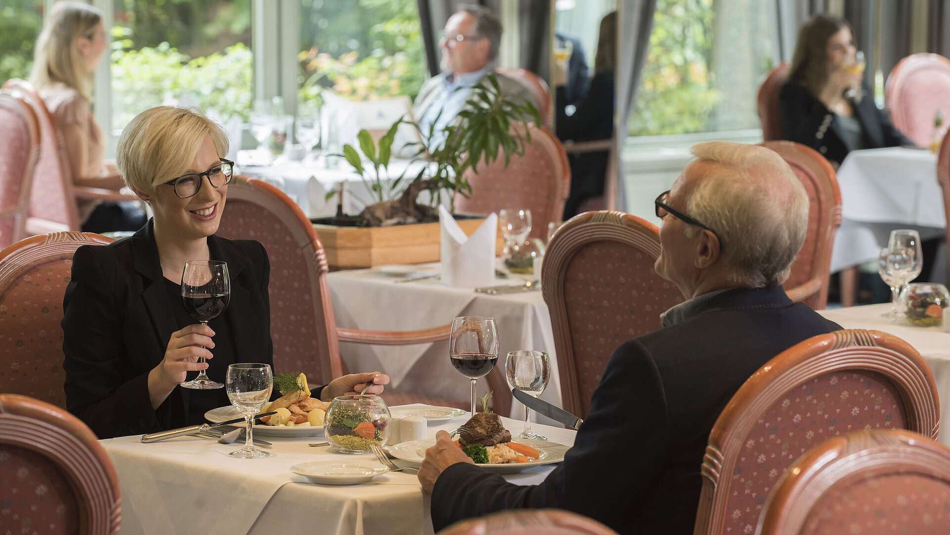 Gäste beim Abendessen im stilvollen Restaurant des Maritim Hotel Bad Salzuflen mit Blick ins Grüne