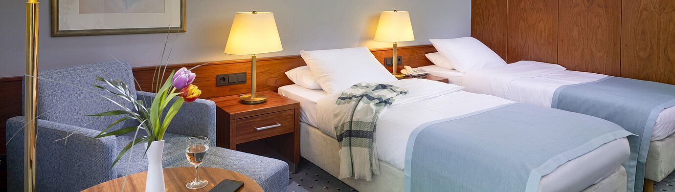 Comfort Twin-Zimmer im Maritim Hotel Darmstadt mit zwei Einzelbetten, gemütlicher Sitzecke und eleganter Inneneinrichtung.
