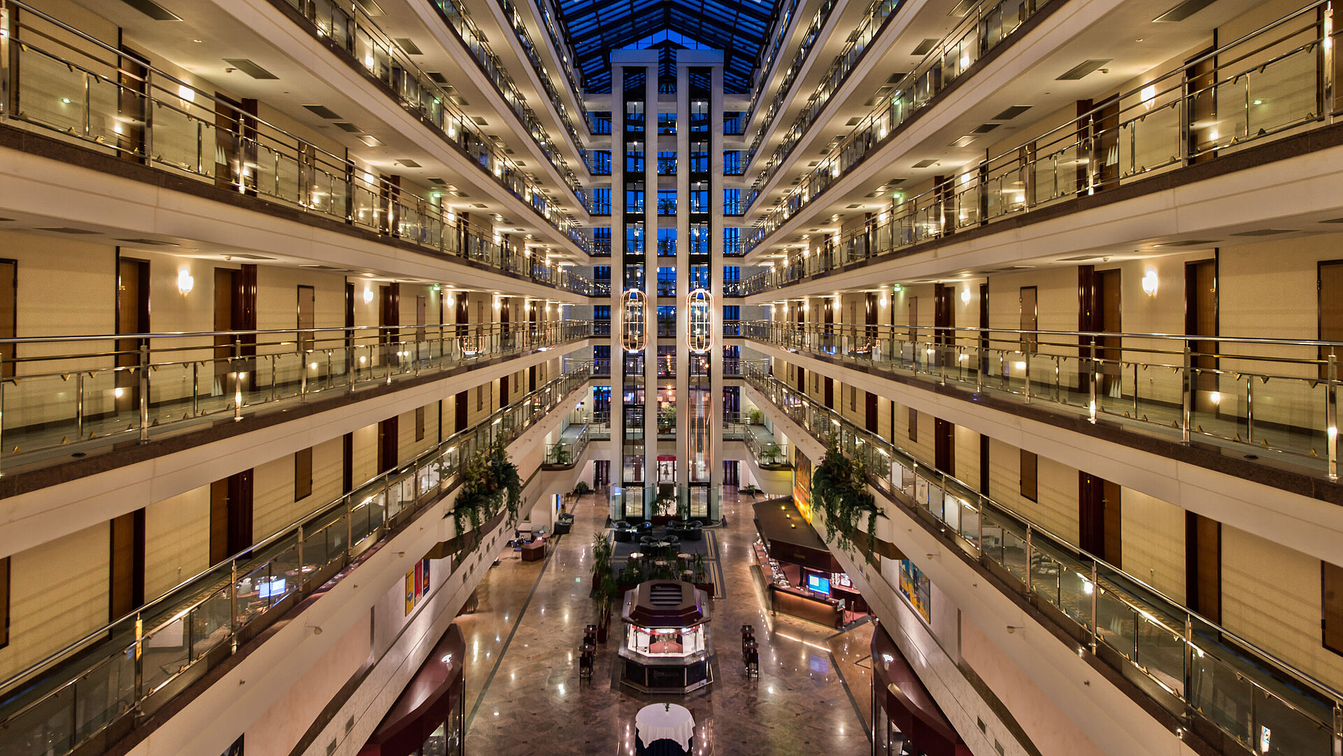 Die großzügige, helle Lobby des Maritim Hotels mit beleuchteten Etagen und moderner Architektur bei Nacht.