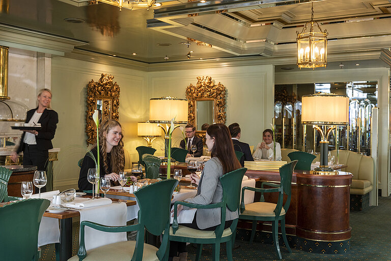 Gäste genießen ihr Essen im eleganten Restaurant La Galerie im Maritim Hotel Köln,umgeben von stilvollen Spiegeln und Lampen