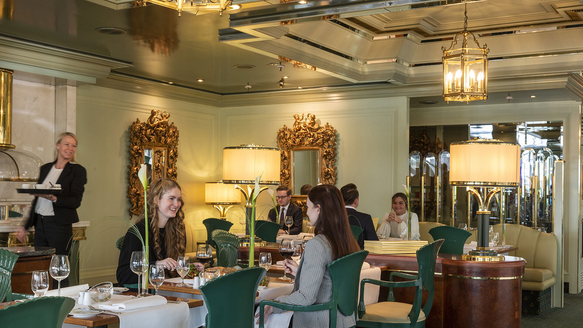 Gäste genießen ihr Essen im eleganten Restaurant La Galerie im Maritim Hotel Köln,umgeben von stilvollen Spiegeln und Lampen